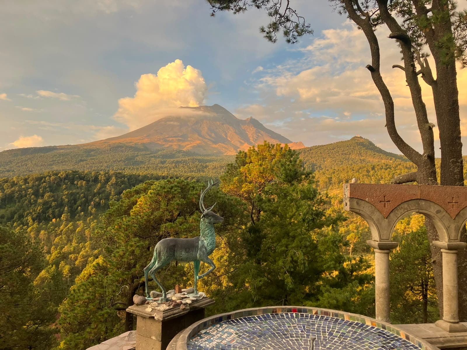 Estatua de venado de bronce junto a la fuente, mirando al volcán